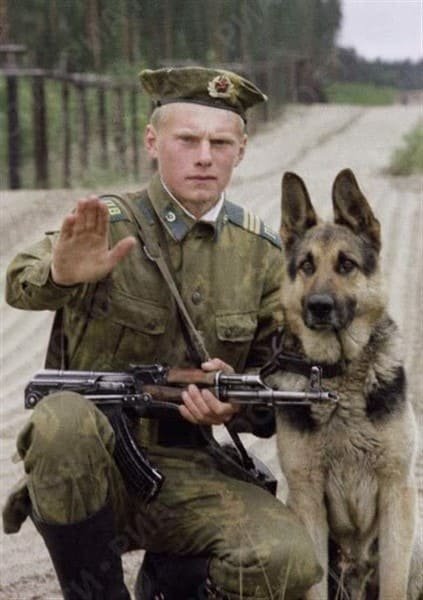 Soviet border guard in field uniform with AK rifle and service dog during Cold War patrol