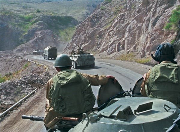 Soviet armored vehicles and military trucks moving along a mountain road in Afghanistan during the Soviet Afghan War