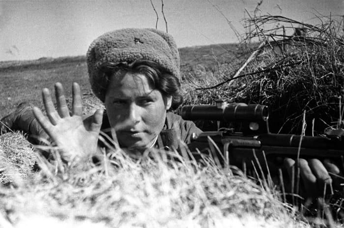 Red Army WW2 uniform: Soviet woman sniper in field uniform aiming rifle, 1944