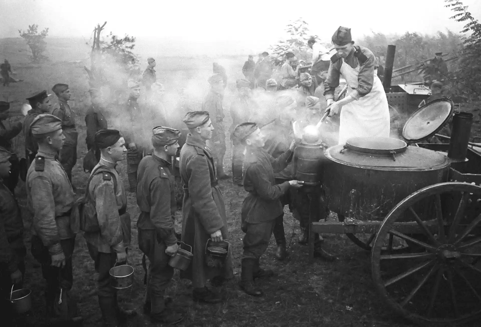 Soviet field kitchen cook serving hot food to soldiers in line during World War II