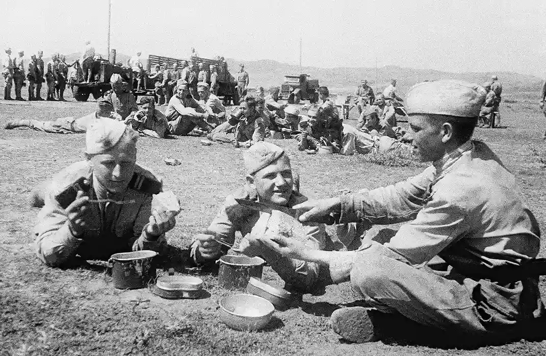 Soviet soldiers eating field rations outdoors during World War II