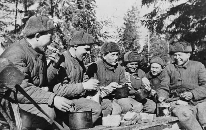 Soviet soldiers eating together in forest during World War II