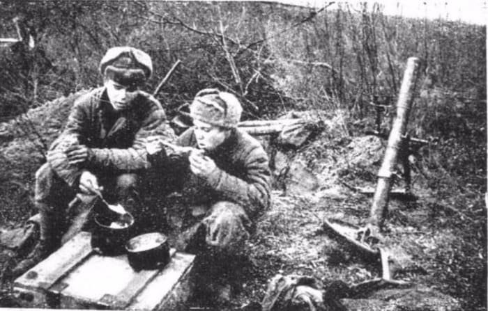 Soviet soldiers eating from mess tins in trench during World War II