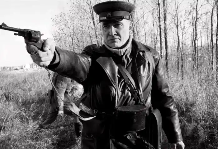 Soviet security officer in leather jacket holding a revolver